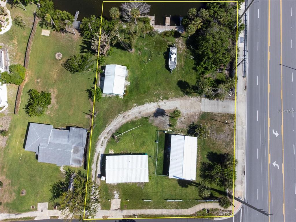 An aerial view shows a waterfront lot with three buildings, a boat, and a dock — 1695 MANOR ROAD, ENGLEWOOD, FL