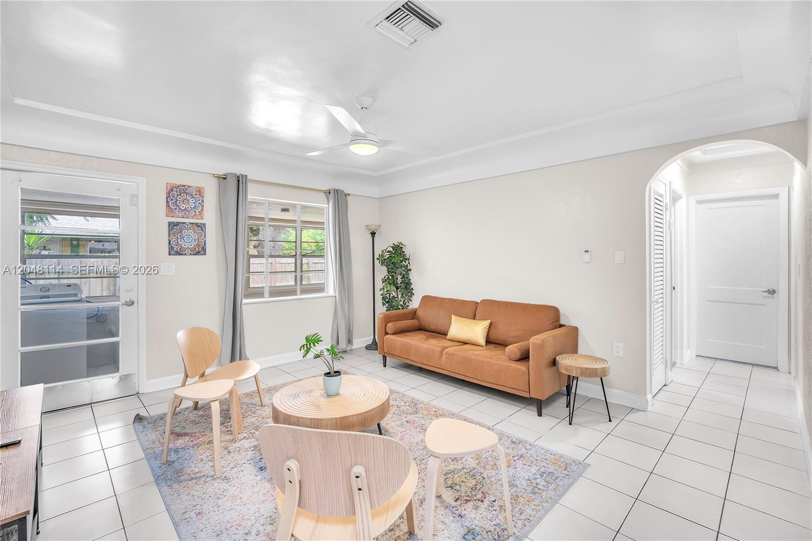 A living room features a brown sofa, light wood furniture, and white tile flooring — 261 SW 15th St # 3, Dania Beach FL 33004, DANIA BEACH, FL
