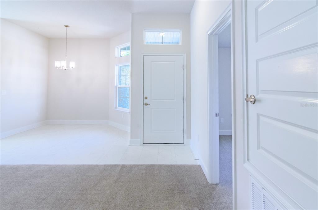A bright entryway features a white front door, a dining area, and carpeted flooring — 14 WENDOVER LANE, PALM COAST, FL