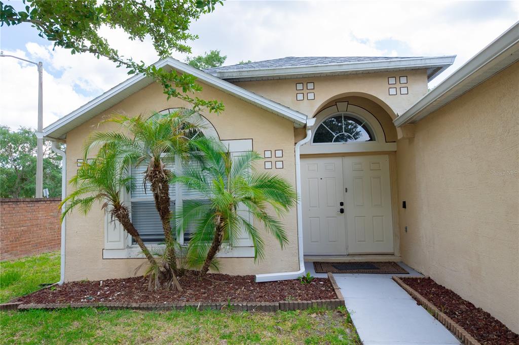 The exterior of a tan house features a double front door and a palm tree — 16686 CORNER COVE WAY, ORLANDO, FL