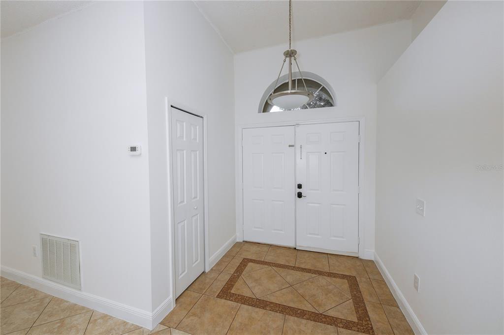 An entryway features white double doors, a tiled floor with a decorative border, and a chandelier — 16686 CORNER COVE WAY, ORLANDO, FL