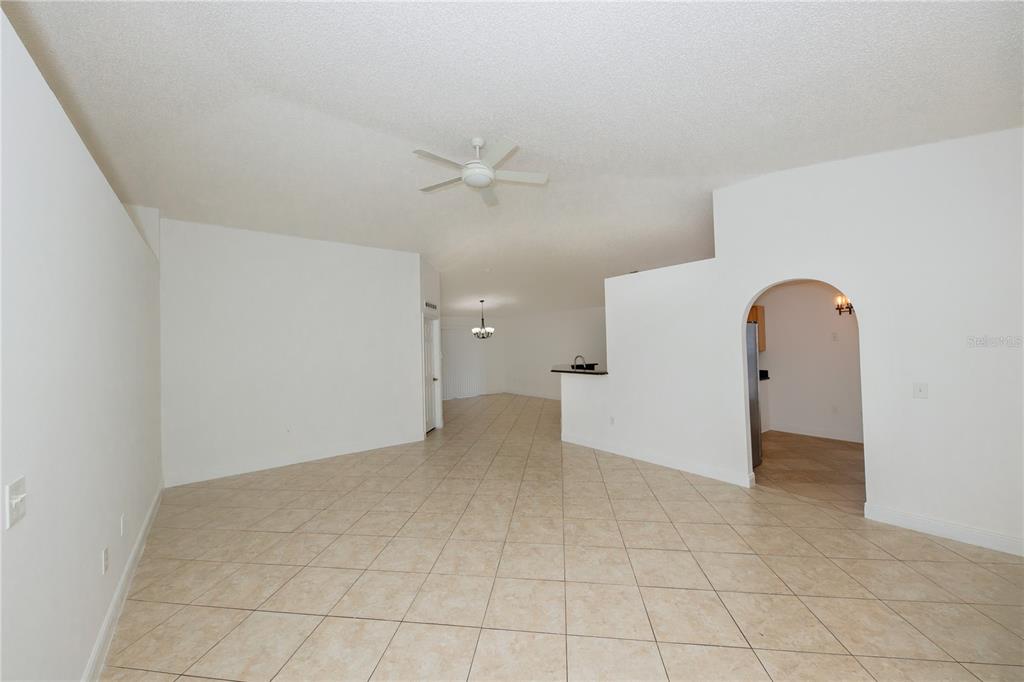 An open-concept living area with white walls, beige tile flooring, and a ceiling fan — 16686 CORNER COVE WAY, ORLANDO, FL