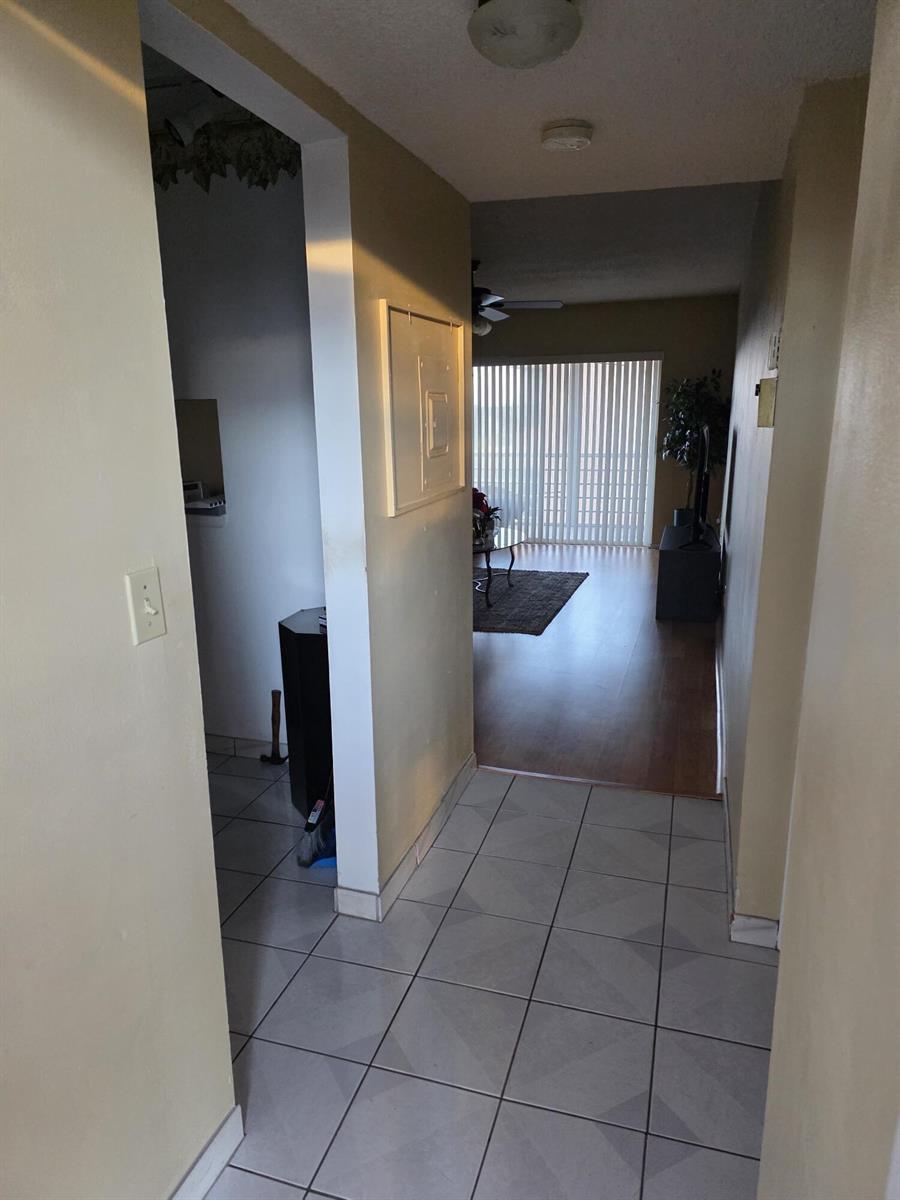 A tiled entryway leads into a living area with wood flooring and vertical blinds — 3048 E Sunrise Lakes Drive E # 412, Sunrise FL 33322, SUNRISE, FL