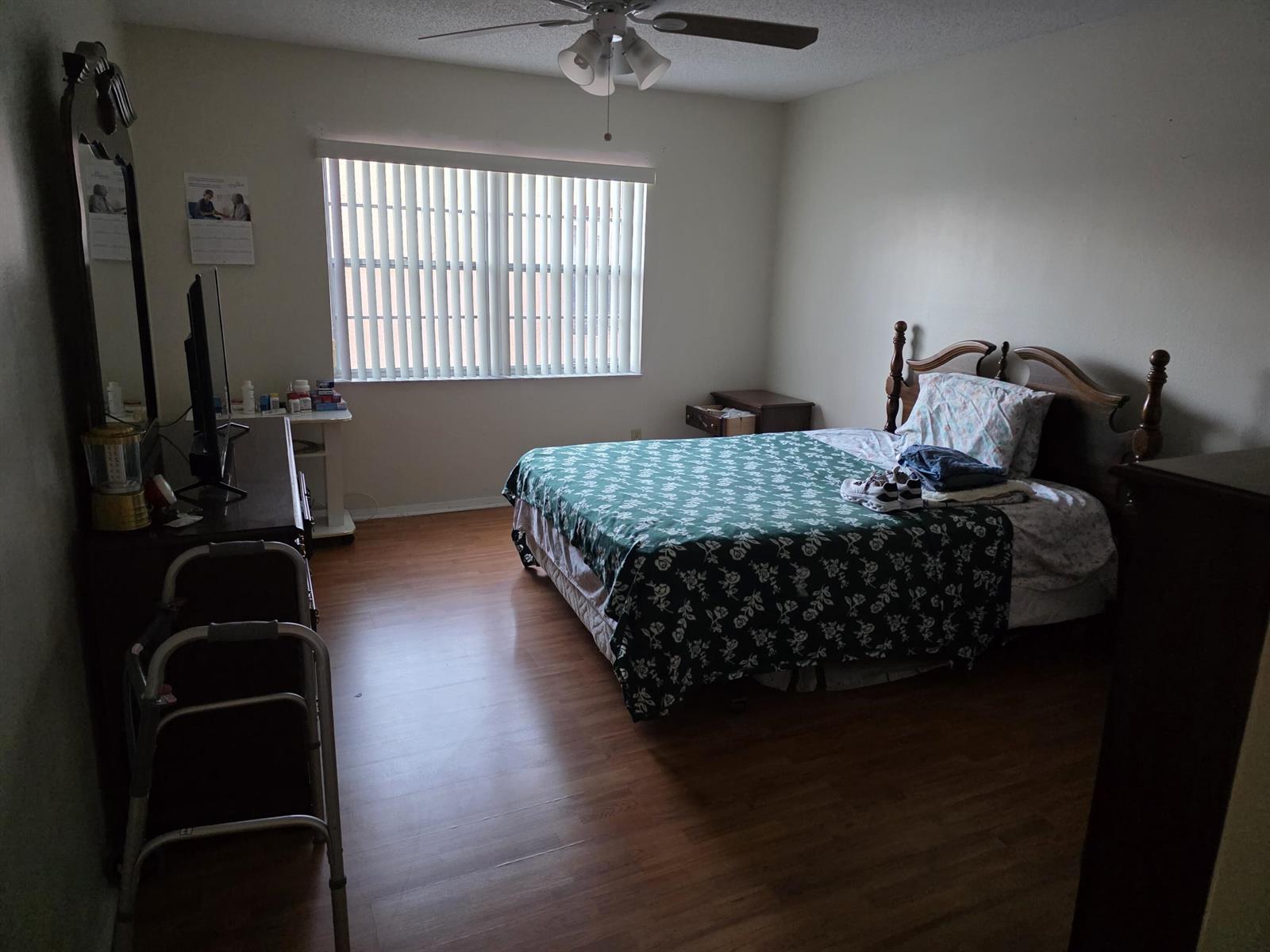 A bedroom features a wooden bed frame, a dresser with a mirror, and wood-look flooring — 3048 E Sunrise Lakes Drive E # 412, Sunrise FL 33322, SUNRISE, FL