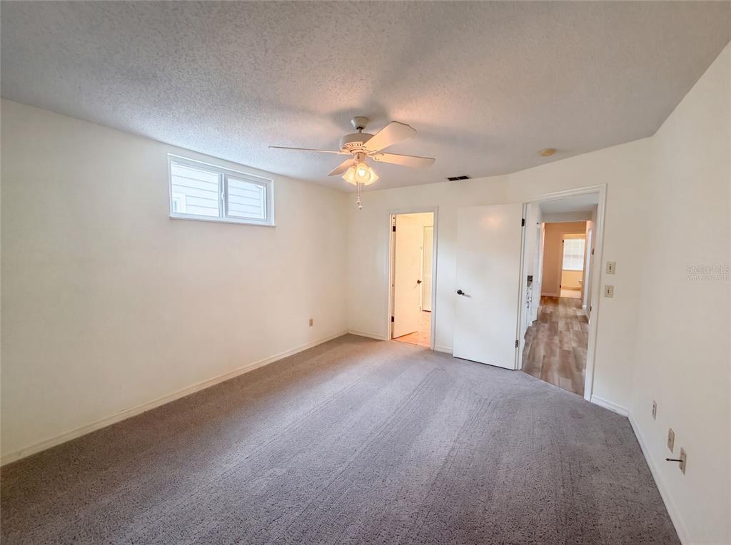 An empty bedroom features gray carpeting, white walls, a ceiling fan, and two doorways — 228 BOB WHITE COURT UNIT 2280, DAYTONA BEACH, FL