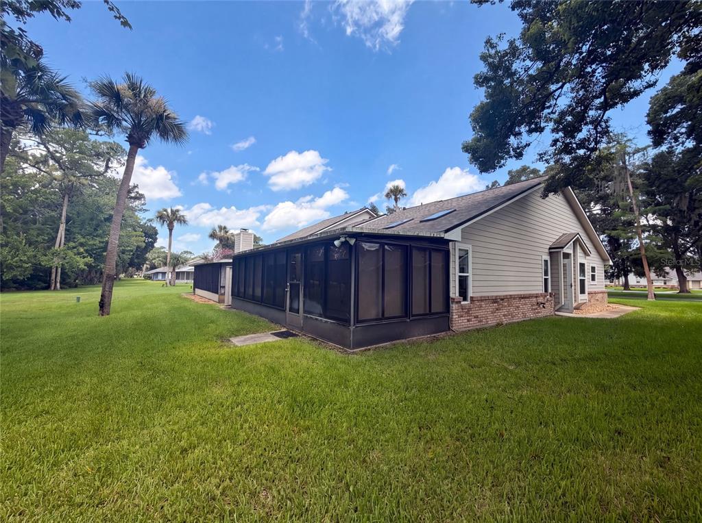 A side view of a house with a large screened-in porch and beige siding — 228 BOB WHITE COURT UNIT 2280, DAYTONA BEACH, FL