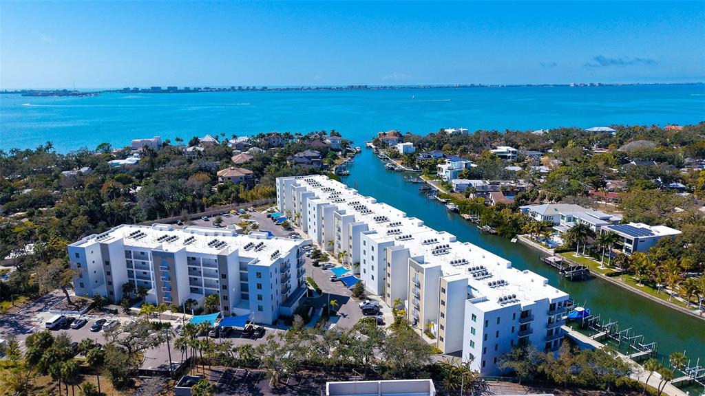 An aerial view shows two large white apartment buildings situated along a canal near water — 1703 N TAMIAMI TRAIL UNIT 511, SARASOTA, FL