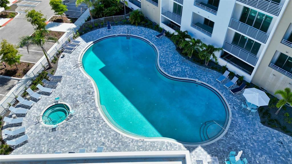 An aerial view shows a kidney-shaped swimming pool and hot tub on a paved patio — 1703 N TAMIAMI TRAIL UNIT 511, SARASOTA, FL