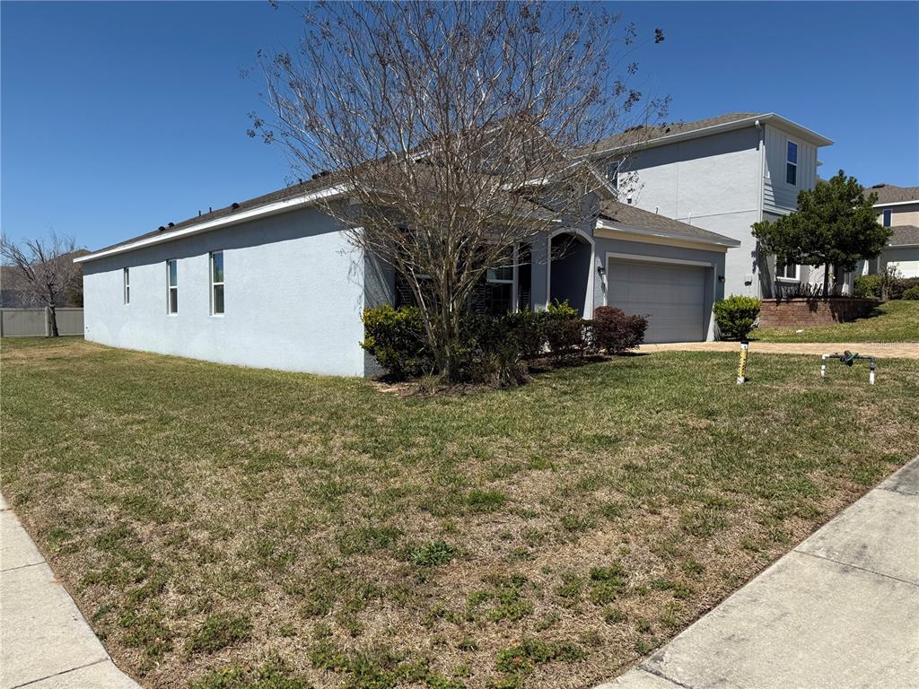 A single-story house with a gray stucco exterior, a garage, and a front lawn — 1501 FINCHBURG STREET, MINNEOLA, FL