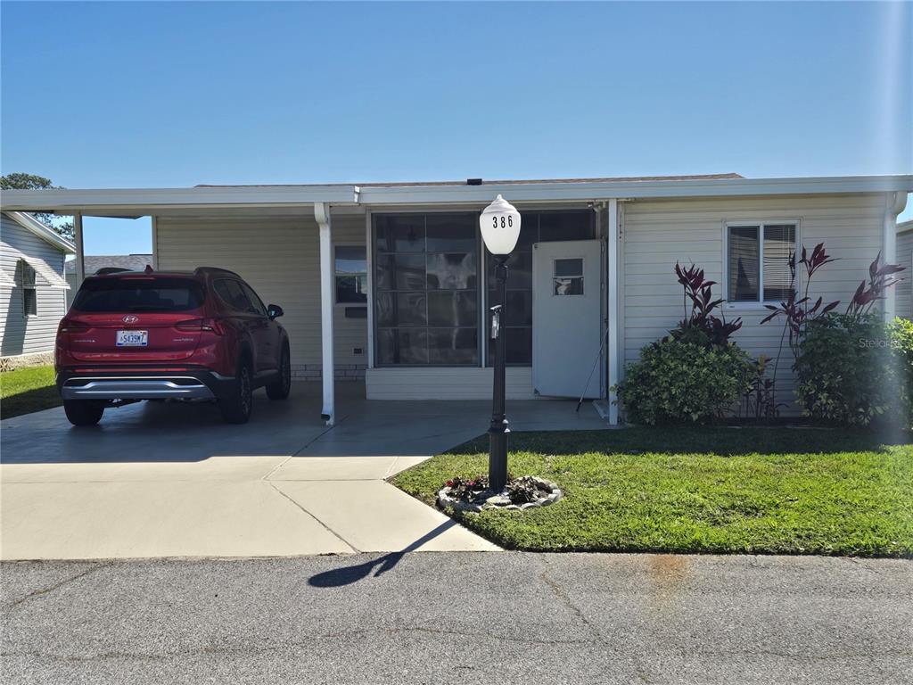 A single-story mobile home features a carport, a red SUV, and a front lawn — 386 TOWNBRIDGE DRIVE, HAINES CITY, FL