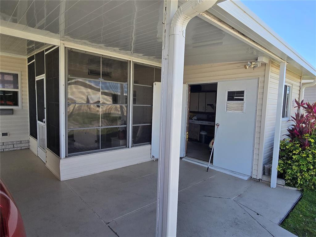A covered concrete patio features a screened-in porch area and a white door leading inside — 386 TOWNBRIDGE DRIVE, HAINES CITY, FL