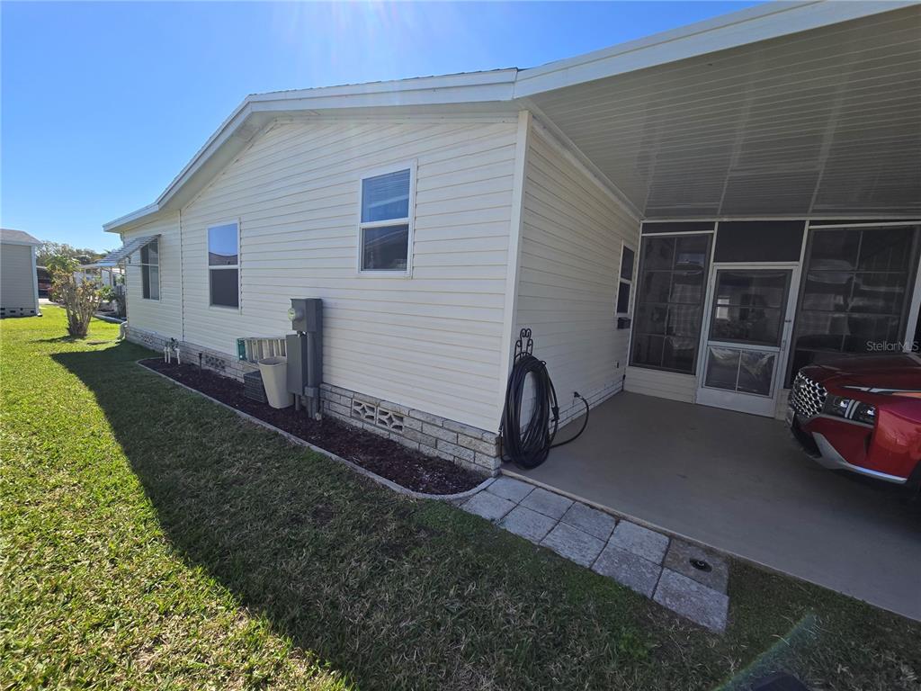The exterior of a light-colored mobile home features a carport, a screened porch, and skirting — 386 TOWNBRIDGE DRIVE, HAINES CITY, FL