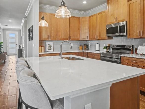 A kitchen features a white quartz island, light wood cabinetry, and stainless steel appliances — 25425 CALUSA DRIVE, PUNTA GORDA, FL