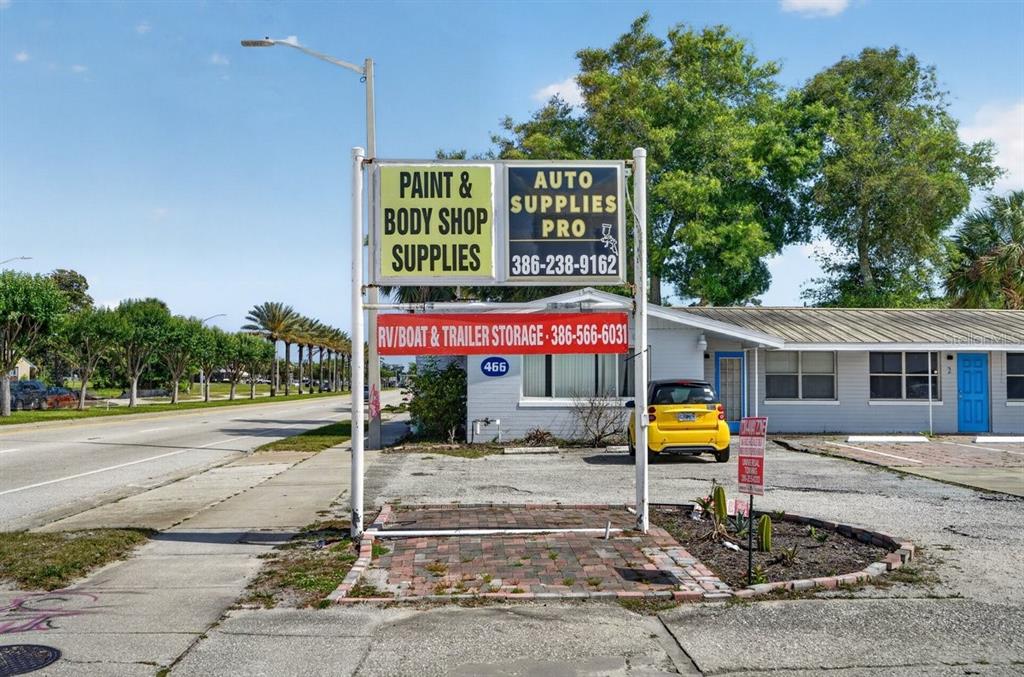 A commercial building with a prominent sign for auto supplies and storage stands near a road — 468 RIDGEWOOD AVENUE, DAYTONA BEACH, FL