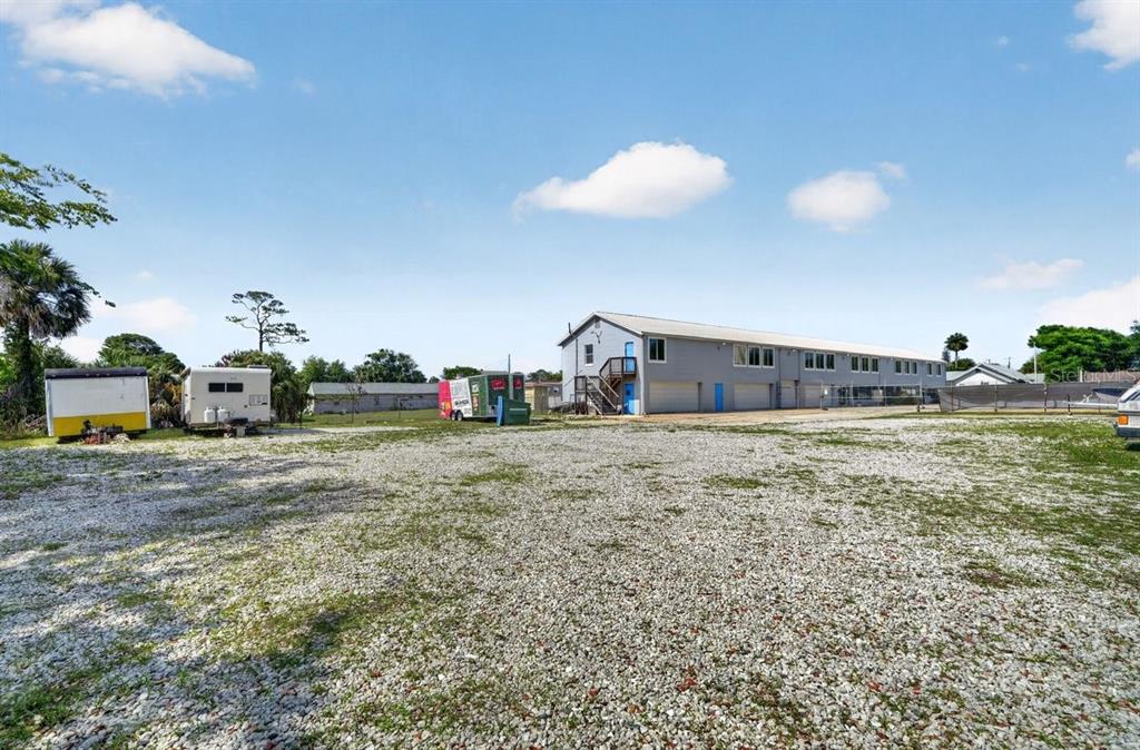 A gravel lot sits in front of a two-story building with several trailers parked nearby — 468 RIDGEWOOD AVENUE, DAYTONA BEACH, FL