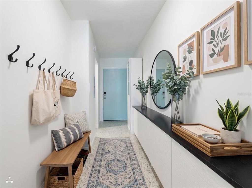 A bright entryway features a wooden bench, wall hooks, a long console, and a mirror — 3700 S ATLANTIC AVENUE UNIT 207, NEW SMYRNA BEACH, FL