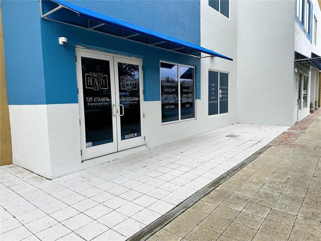 The exterior of a commercial building features a blue and white facade with glass doors — 1100 CLEVELAND STREET, CLEARWATER, FL