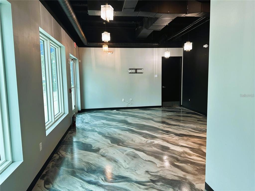 An empty room features a high black ceiling, pendant lights, and a marbled epoxy floor — 1100 CLEVELAND STREET, CLEARWATER, FL