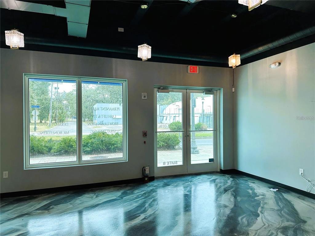 An empty commercial space features a glossy marbled floor, black ceiling, and glass entry doors — 1100 CLEVELAND STREET, CLEARWATER, FL