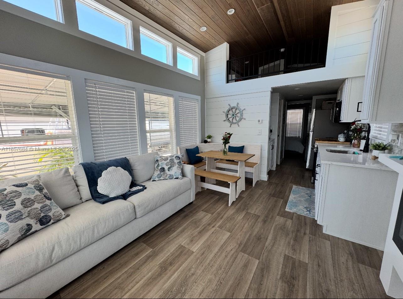 A bright living room and kitchen area features wood-look flooring, white shiplap walls, and a loft — 325 Calusa St 302, Key Largo FL 33037, KEY LARGO, FL
