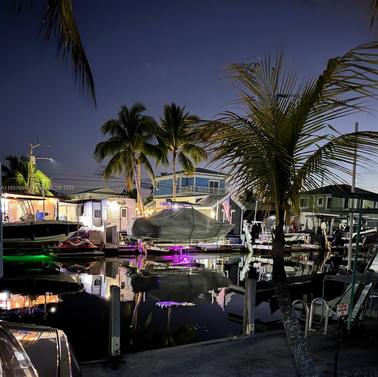 A canal-side view at night featuring boats docked in front of houses and palm trees — 325 Calusa St 302, Key Largo FL 33037, KEY LARGO, FL