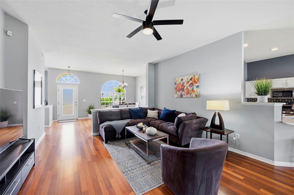 A living room features hardwood floors, a sectional sofa, a ceiling fan, and an area rug — 29609 EAGLE STATION DRIVE, WESLEY CHAPEL, FL