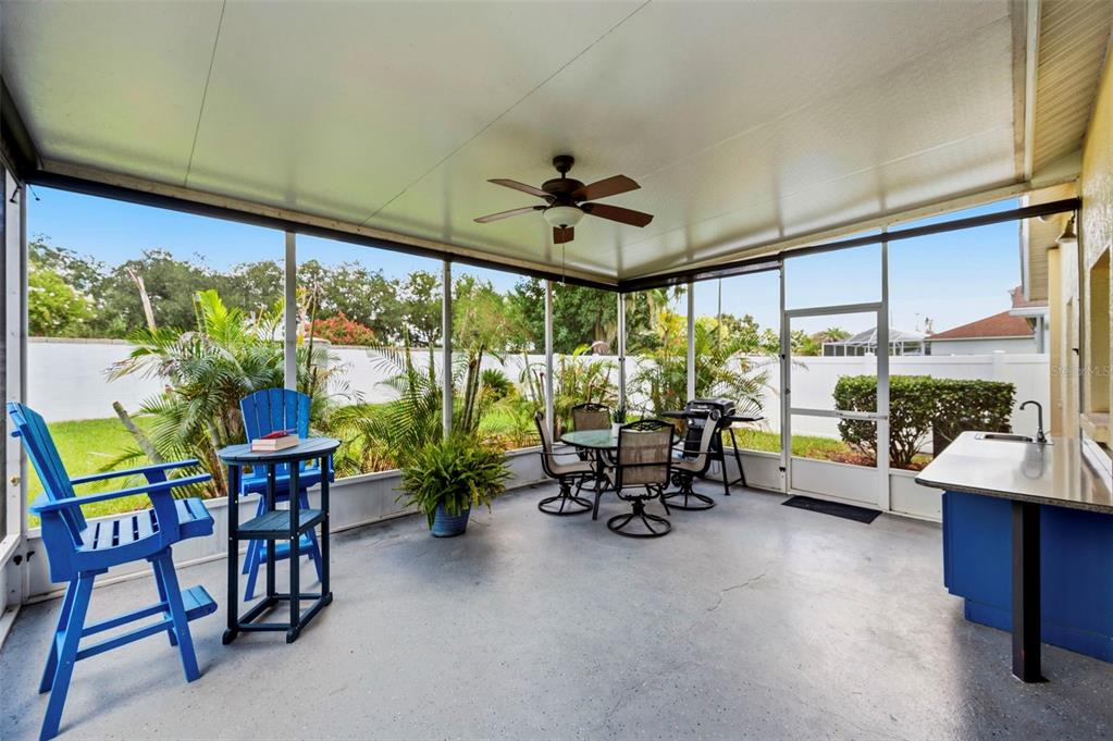 A screened-in patio features a ceiling fan, outdoor dining set, and a small kitchenette area — 29609 EAGLE STATION DRIVE, WESLEY CHAPEL, FL