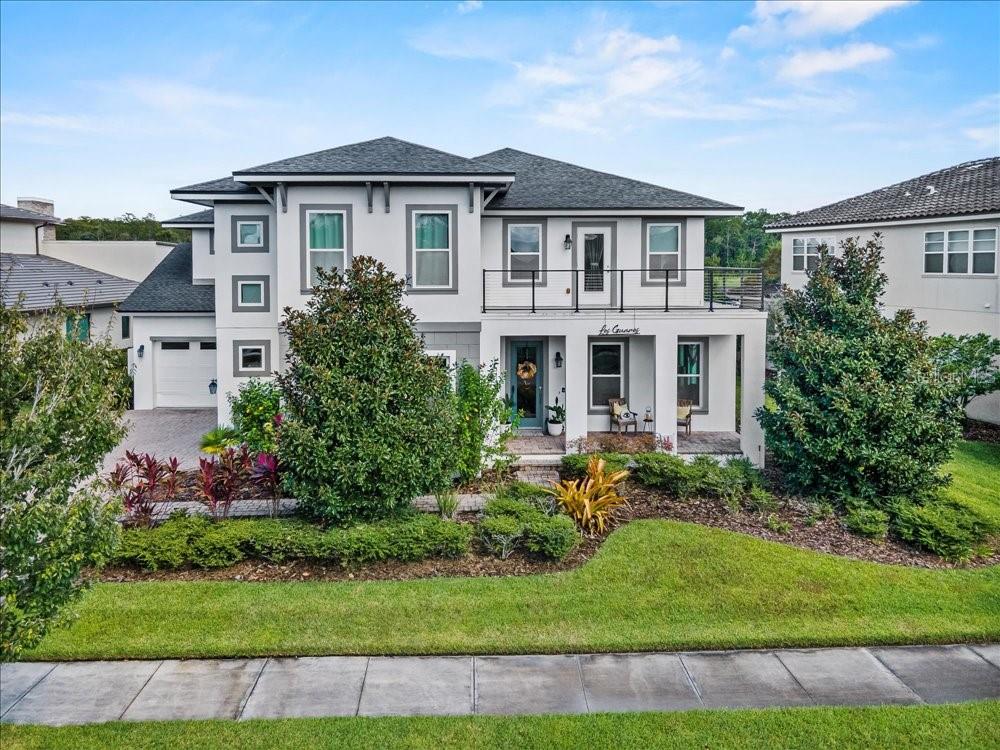 A two-story suburban house with a white exterior, a front balcony, and a paved driveway — 14129 CORRIGAN AVENUE, ORLANDO, FL