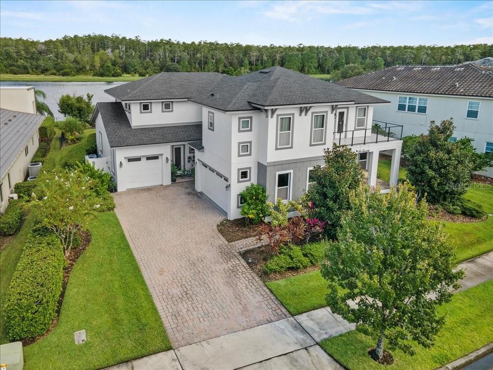 An aerial view of a two-story house with a paved driveway and a waterfront backyard — 14129 CORRIGAN AVENUE, ORLANDO, FL