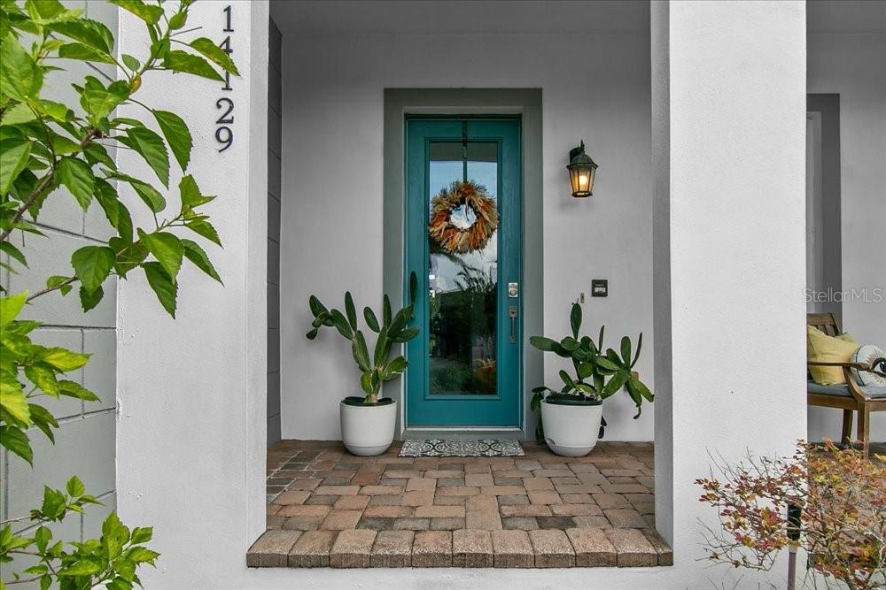 A front porch features a teal door, two potted cacti, and a brick floor — 14129 CORRIGAN AVENUE, ORLANDO, FL
