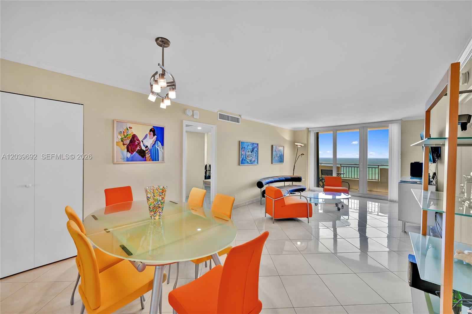 A bright living and dining area features orange chairs, a glass table, and ocean views — 3180 S Ocean Dr # 1610, Hallandale Beach FL 33009, HALLANDALE BEACH, FL