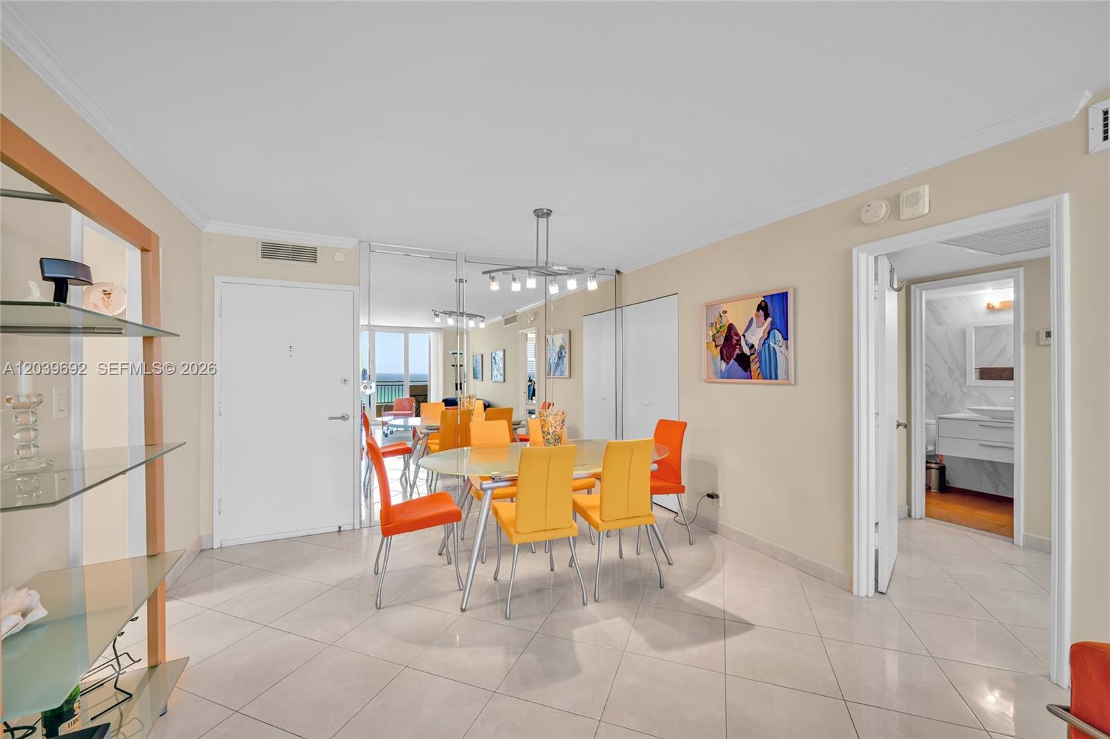 A dining area features a glass table with orange and yellow chairs and mirrored walls — 3180 S Ocean Dr # 1610, Hallandale Beach FL 33009, HALLANDALE BEACH, FL
