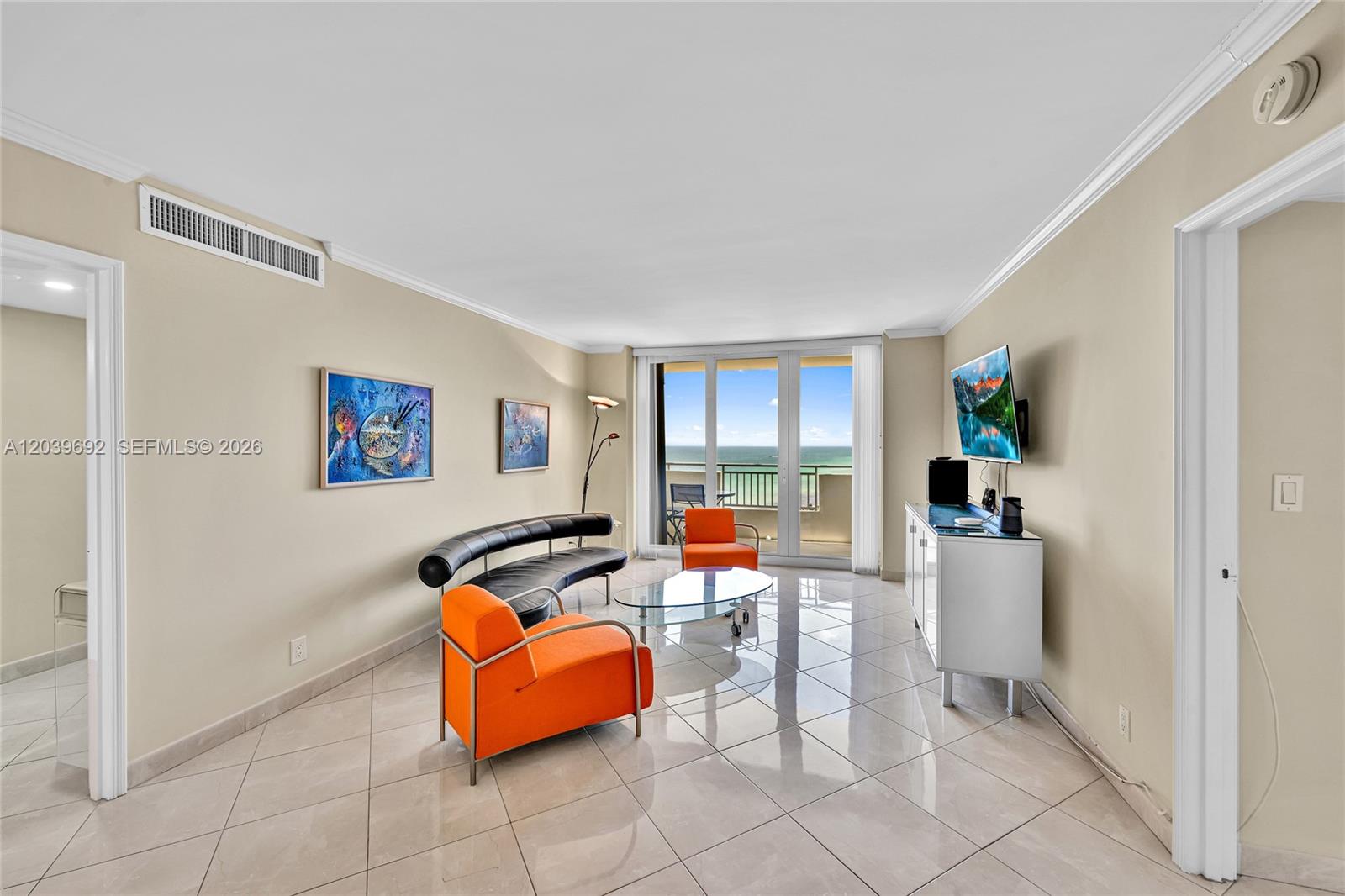 A living room features tile flooring, orange armchairs, a curved sofa, and a balcony view — 3180 S Ocean Dr # 1610, Hallandale Beach FL 33009, HALLANDALE BEACH, FL