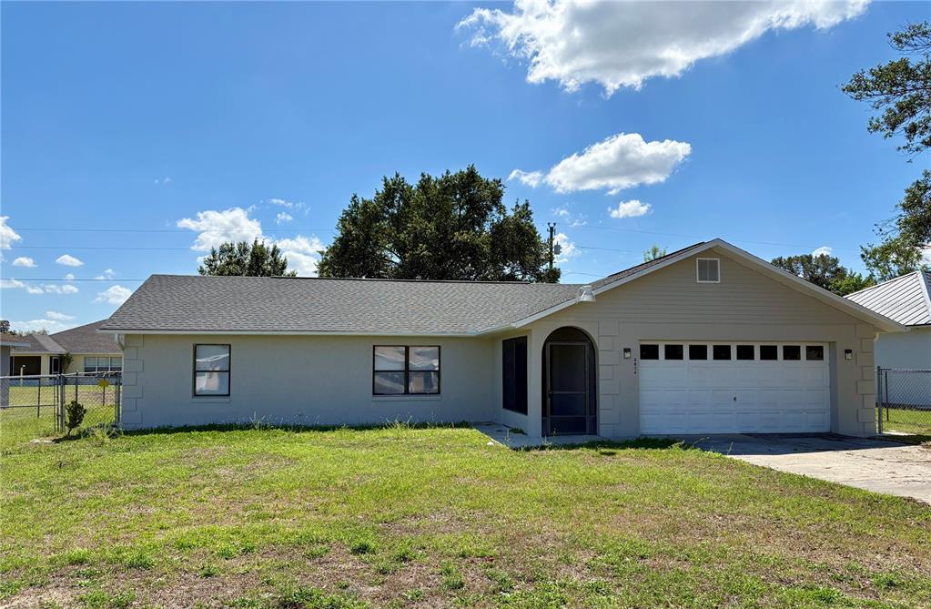 A single-story house with a beige exterior, a two-car garage, and a grassy front yard — 2870 SW 143RD PLACE ROAD, OCALA, FL
