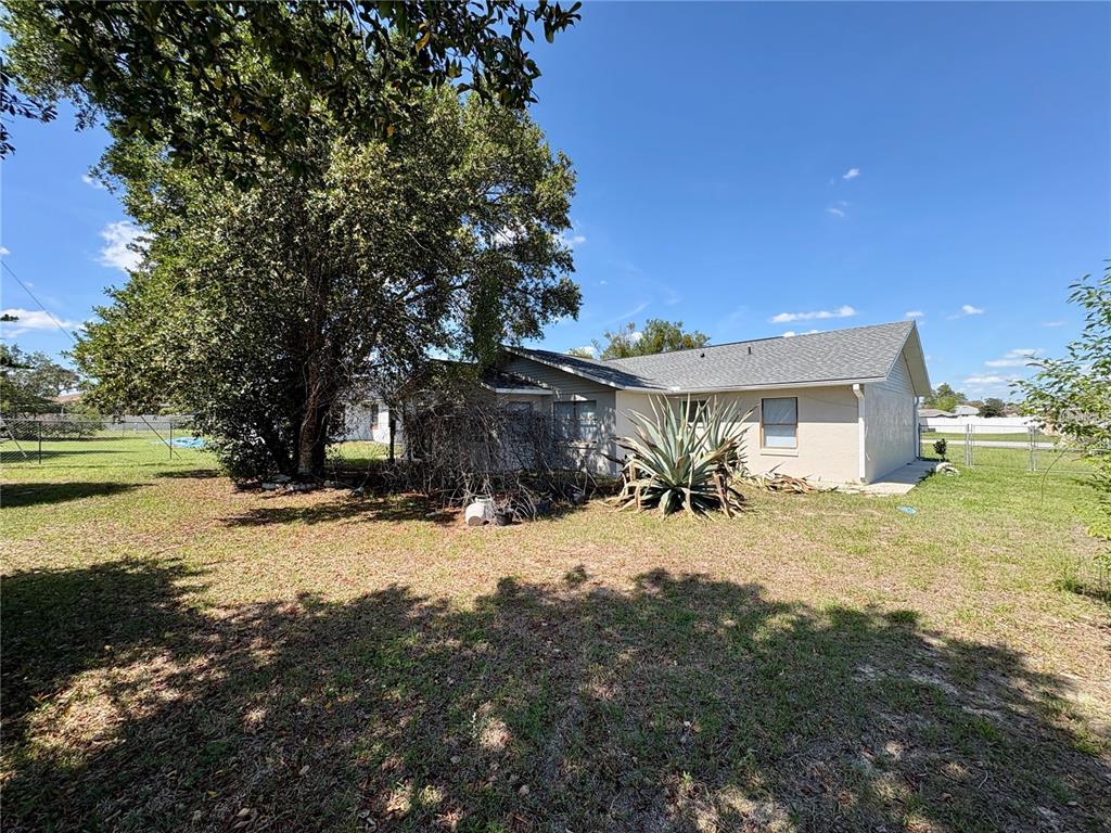 The exterior of a single-story house features a large tree, an agave plant, and lawn — 2870 SW 143RD PLACE ROAD, OCALA, FL