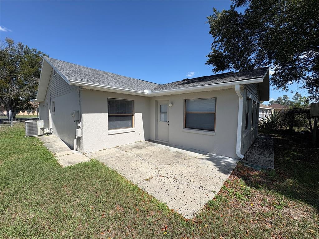 The exterior of a house features a concrete patio, light-colored stucco walls, and a roof — 2870 SW 143RD PLACE ROAD, OCALA, FL