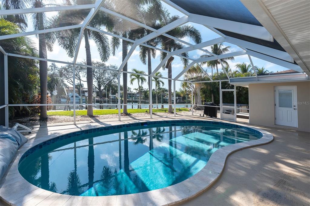 A screened-in pool area overlooks a canal with palm trees and a boat dock — 4200 46TH AVENUE S, ST PETERSBURG, FL