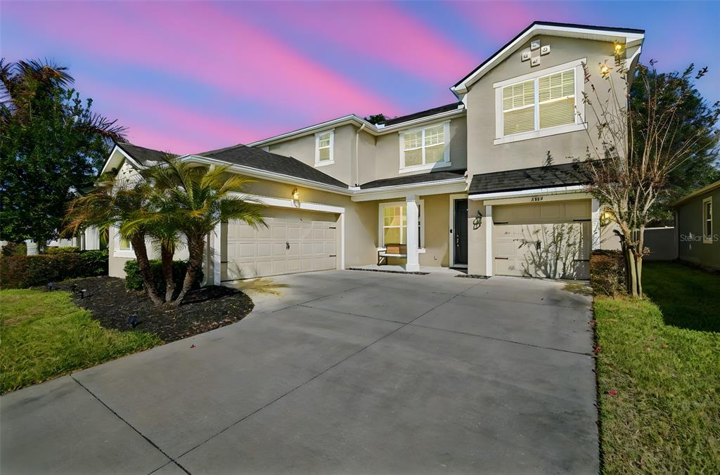 A two-story suburban house with a concrete driveway, two garage doors, and a front porch — 2604 VALLEY SUNSET LANE, VALRICO, FL