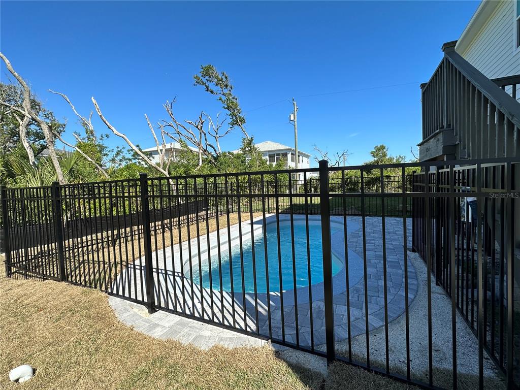 A fenced backyard features a rectangular swimming pool surrounded by gray stone pavers — 37 ATLANTIC DRIVE, PALM COAST, FL
