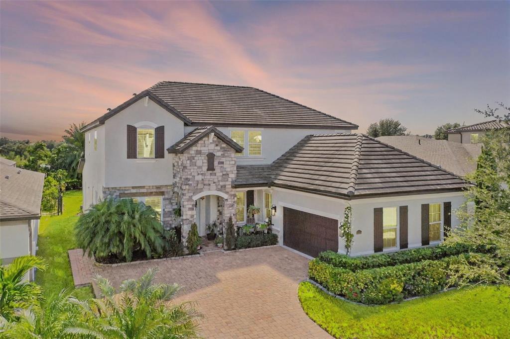 A two-story house with a stone facade, tile roof, and a brick paver driveway — 1711 AMSEL FALLS PARK TERRACE, WINTER GARDEN, FL