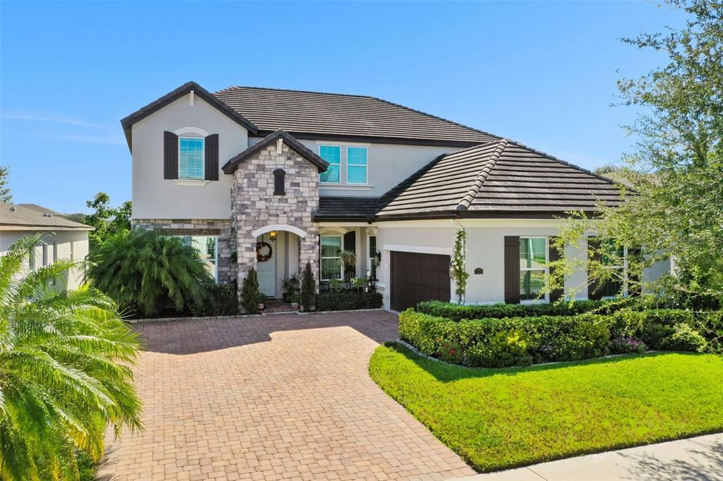 A two-story house with a stone facade, dark tile roof, and a paved driveway — 1711 AMSEL FALLS PARK TERRACE, WINTER GARDEN, FL