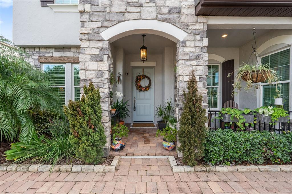 The front entrance features a stone-faced archway, a light blue door, and a brick walkway — 1711 AMSEL FALLS PARK TERRACE, WINTER GARDEN, FL