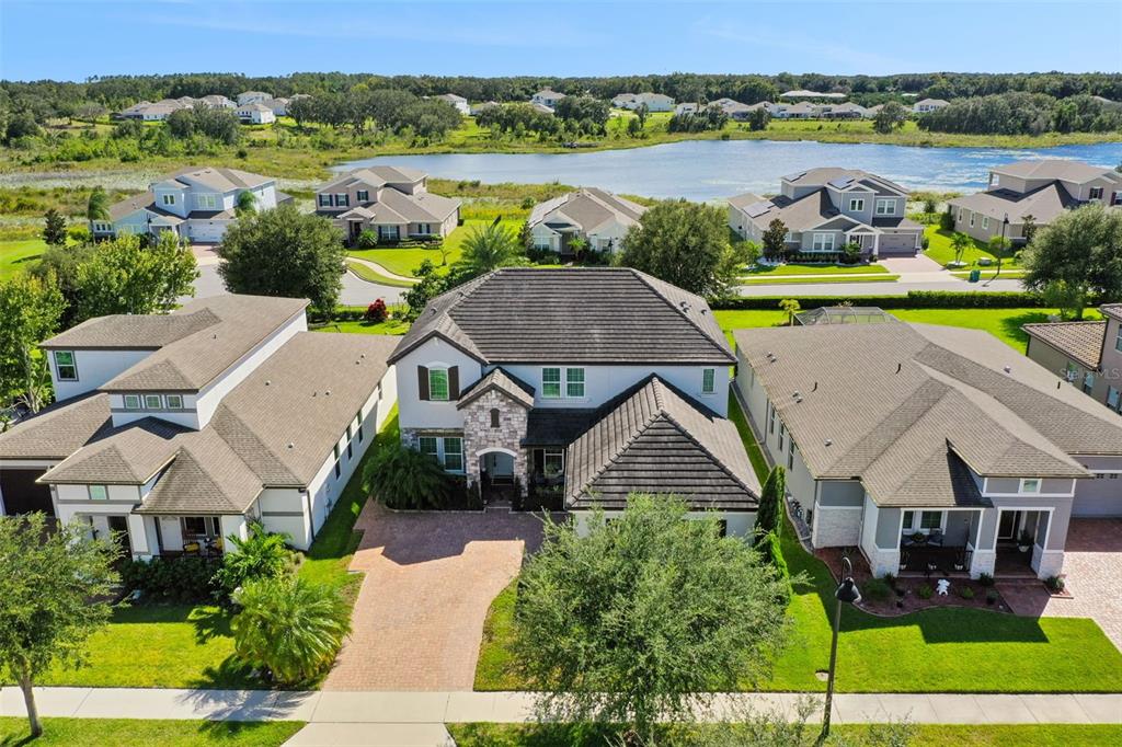 An aerial view shows a two-story suburban house with a brick driveway and tile roof — 1711 AMSEL FALLS PARK TERRACE, WINTER GARDEN, FL