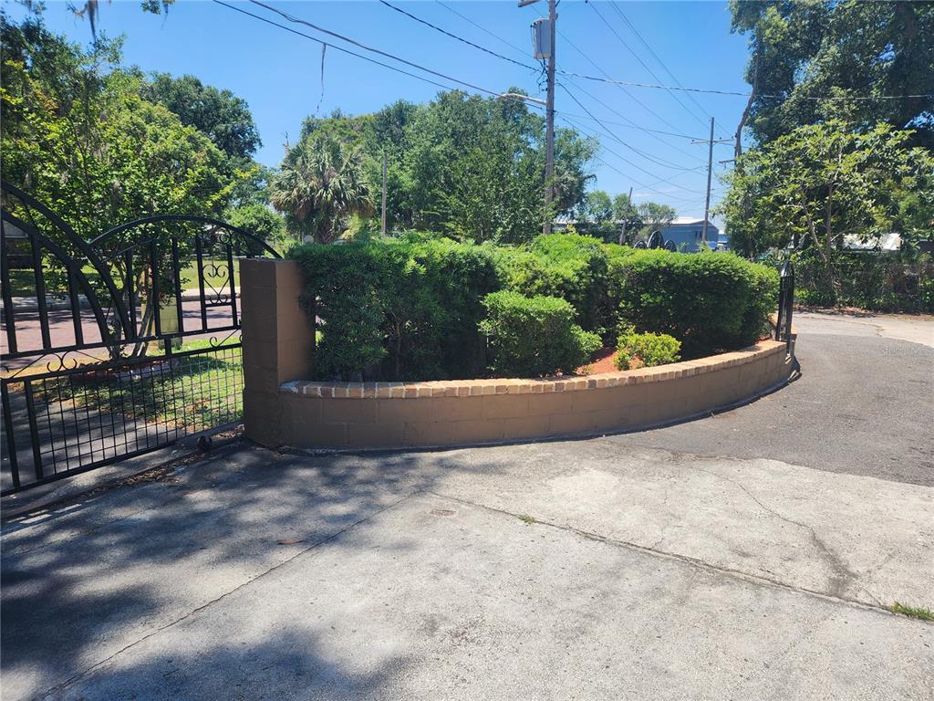 A curved concrete block wall with a brick cap sits in front of green bushes — 921 GRAND STREET, ORLANDO, FL