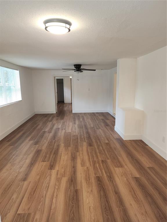 An empty room features wood-look flooring, white walls, a ceiling fan, and a flush-mount light — 921 GRAND STREET, ORLANDO, FL