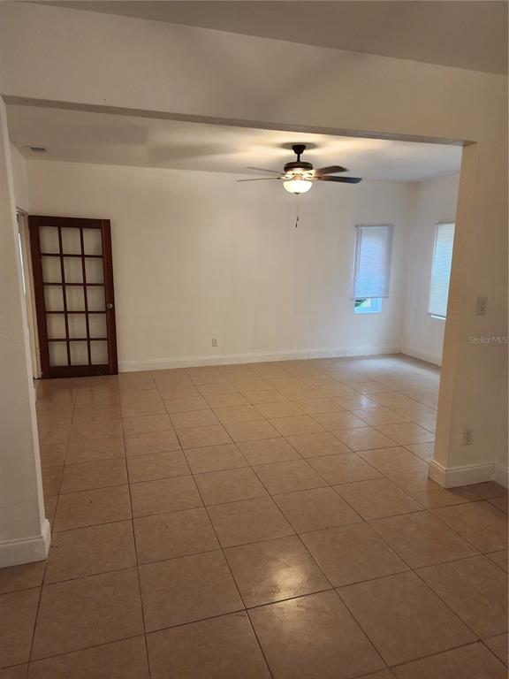 An empty room with beige tile flooring, white walls, a ceiling fan, and French doors — 921 GRAND STREET, ORLANDO, FL