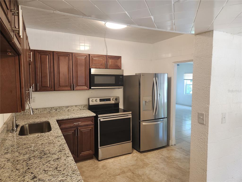 A kitchen features dark wood cabinets, granite countertops, stainless steel appliances, and tiled flooring — 921 GRAND STREET, ORLANDO, FL