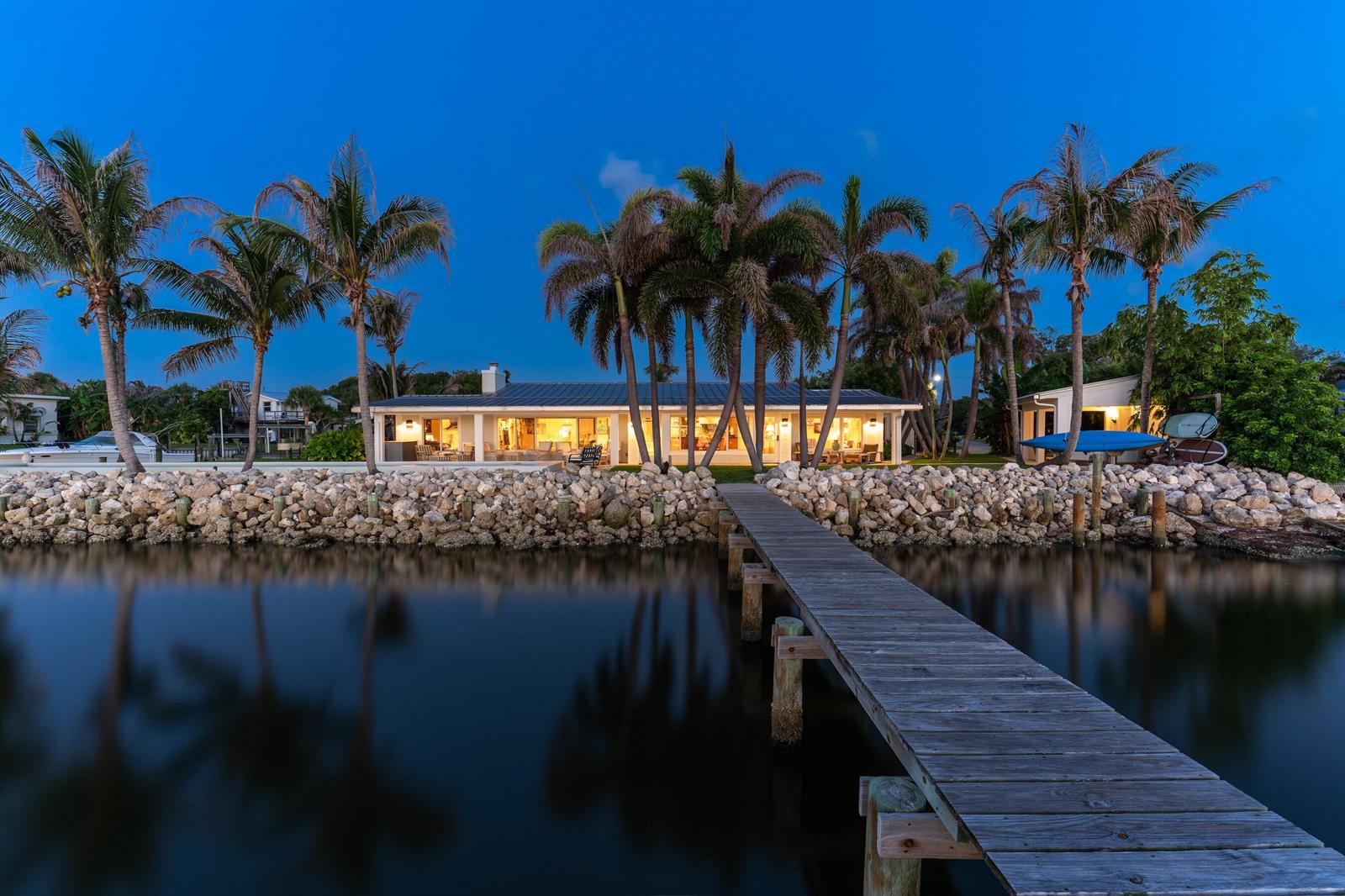 A waterfront house with a wooden dock and palm trees at dusk — FORT PIERCE, FL