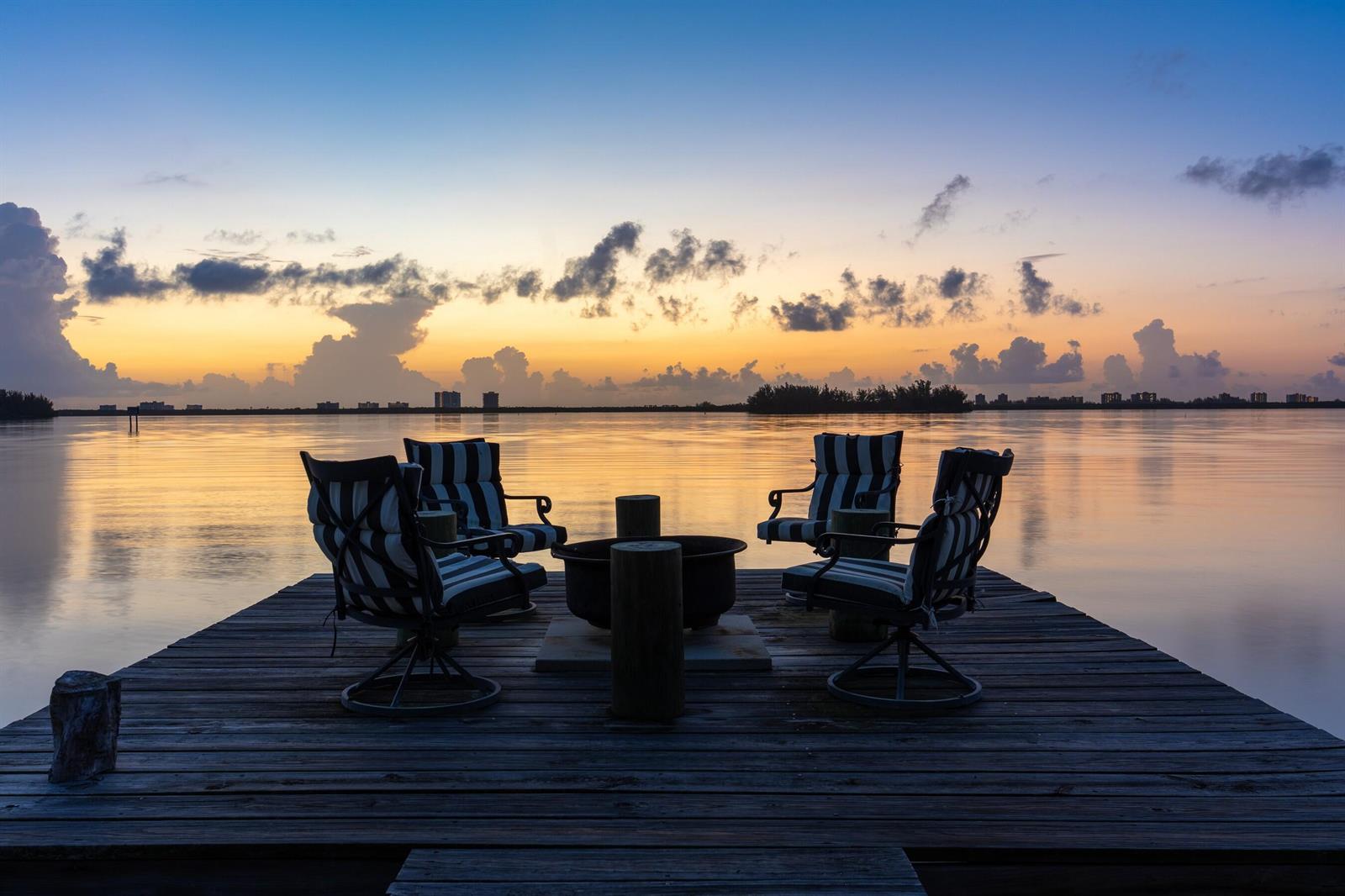 Four chairs surround a fire pit on a wooden dock overlooking a calm body of water — FORT PIERCE, FL