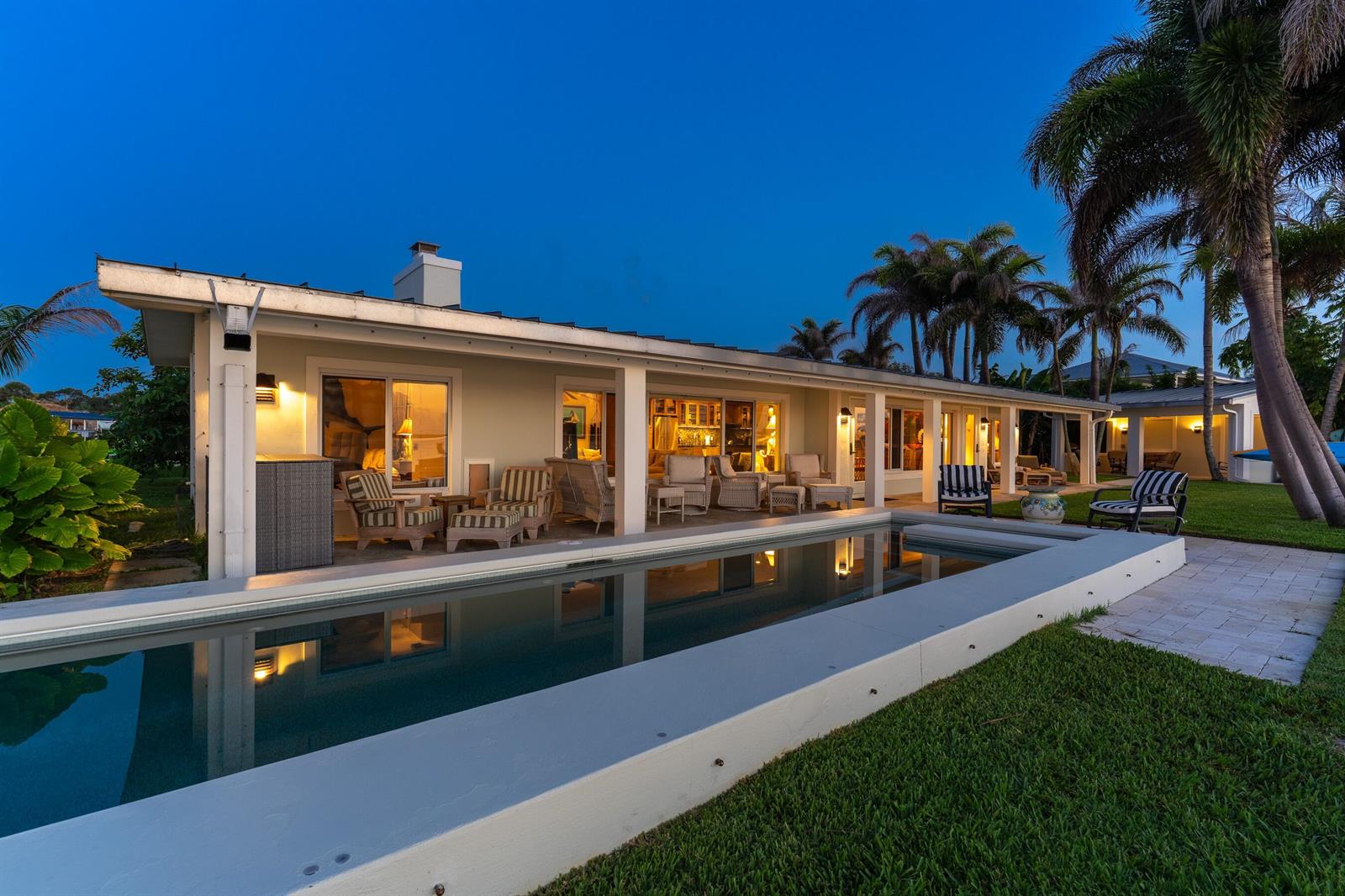 A long swimming pool sits in front of a house with a covered patio at dusk — FORT PIERCE, FL